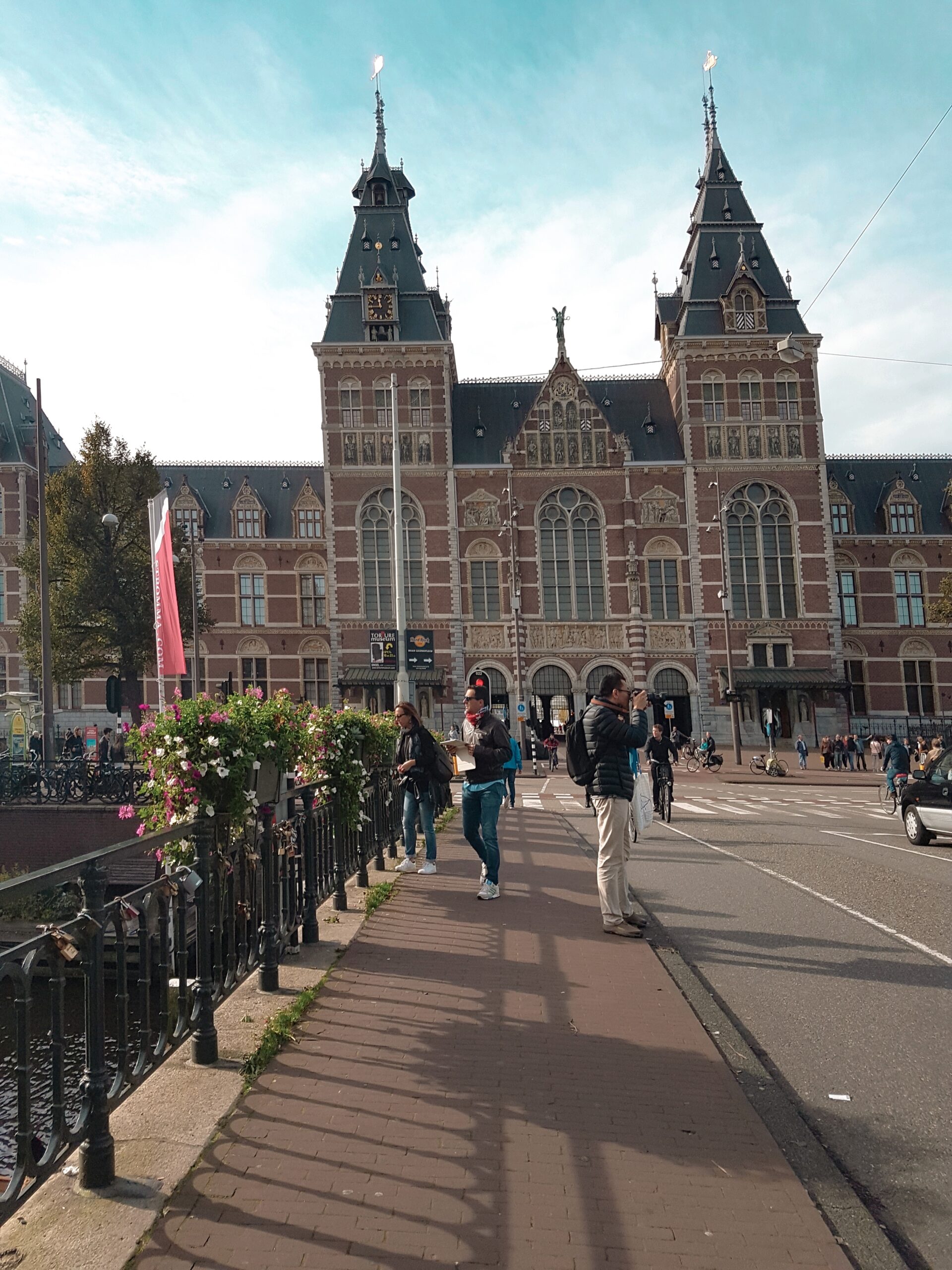 A charming view of Amsterdam’s iconic canals lined with historic, narrow townhouses. The scene captures colorful bicycles parked along the cobblestone streets, with small boats gently floating on the calm water. A soft, golden light from the setting sun reflects off the water, highlighting the city’s blend of classic architecture and vibrant urban life.