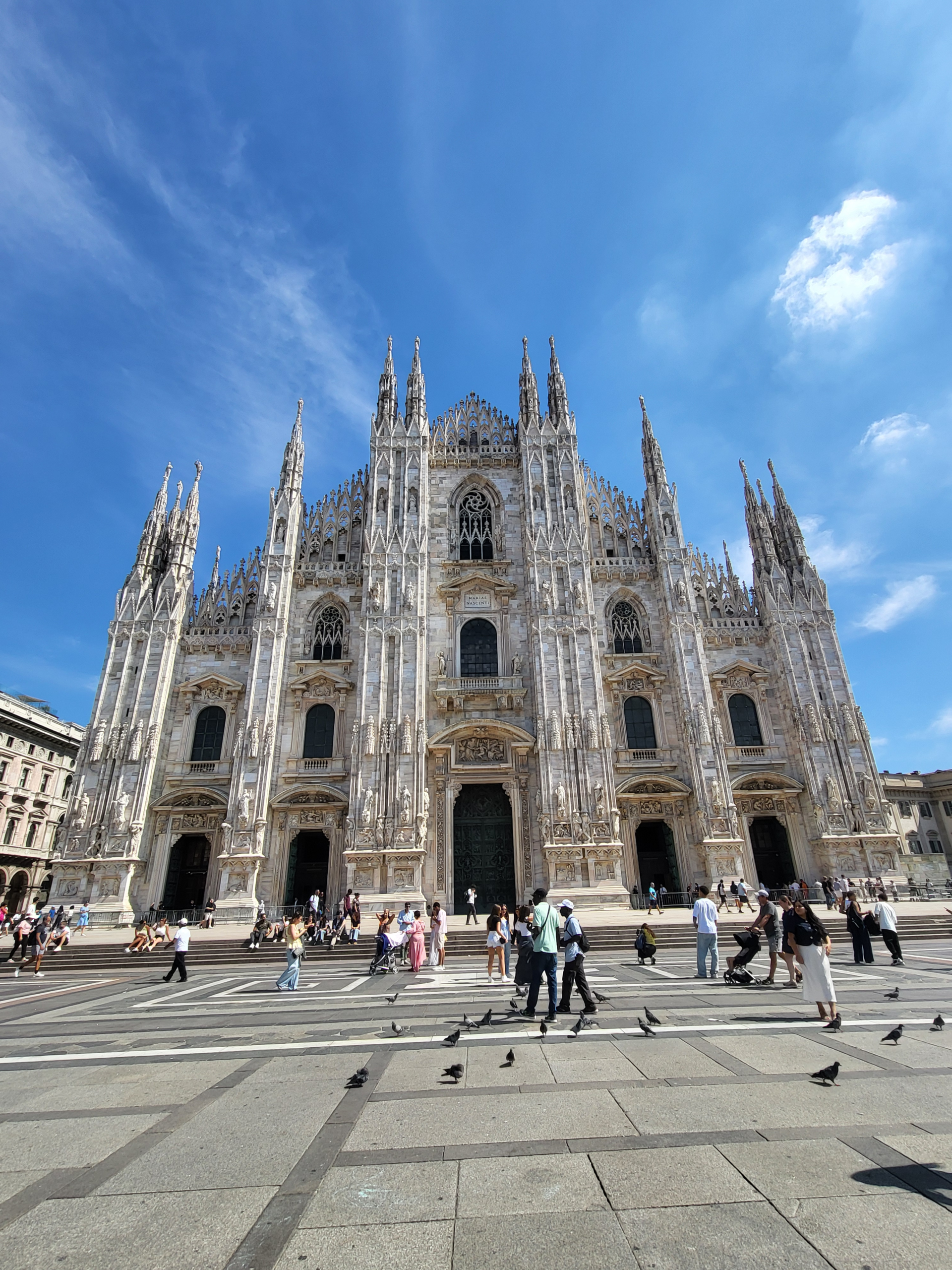 The Duomo di Milano, the magnificent Gothic cathedral in Milan, Italy, showcasing its intricate marble façade, soaring spires, and statues under a clear blue sky in Piazza del Duomo.