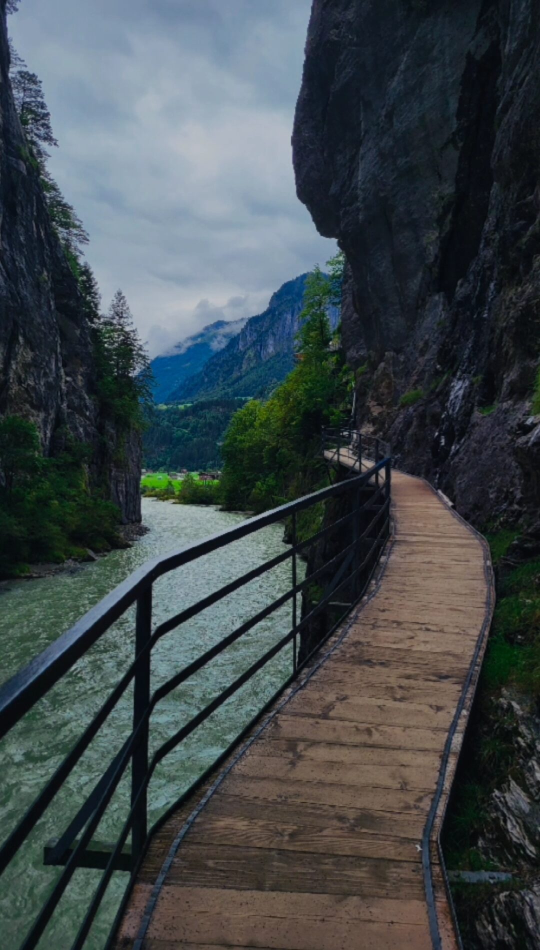 A dramatic narrow limestone canyon carved by the Aare River near Meiringen in central Switzerland, featuring turquoise glacial water, towering vertical rock walls, and a wooden walkway leading visitors through the scenic Aare Gorge.